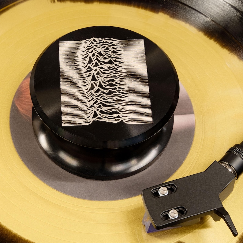 Pulsar waveform engraved on a record weight resting on yellow vinyl